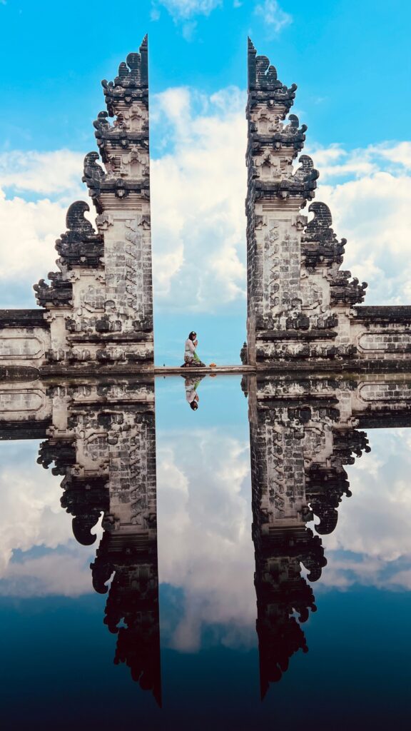 Iconic Balinese temple gate with a reflection pool under a blue sky, representing Bali's rich culture and popular tourist attractions.