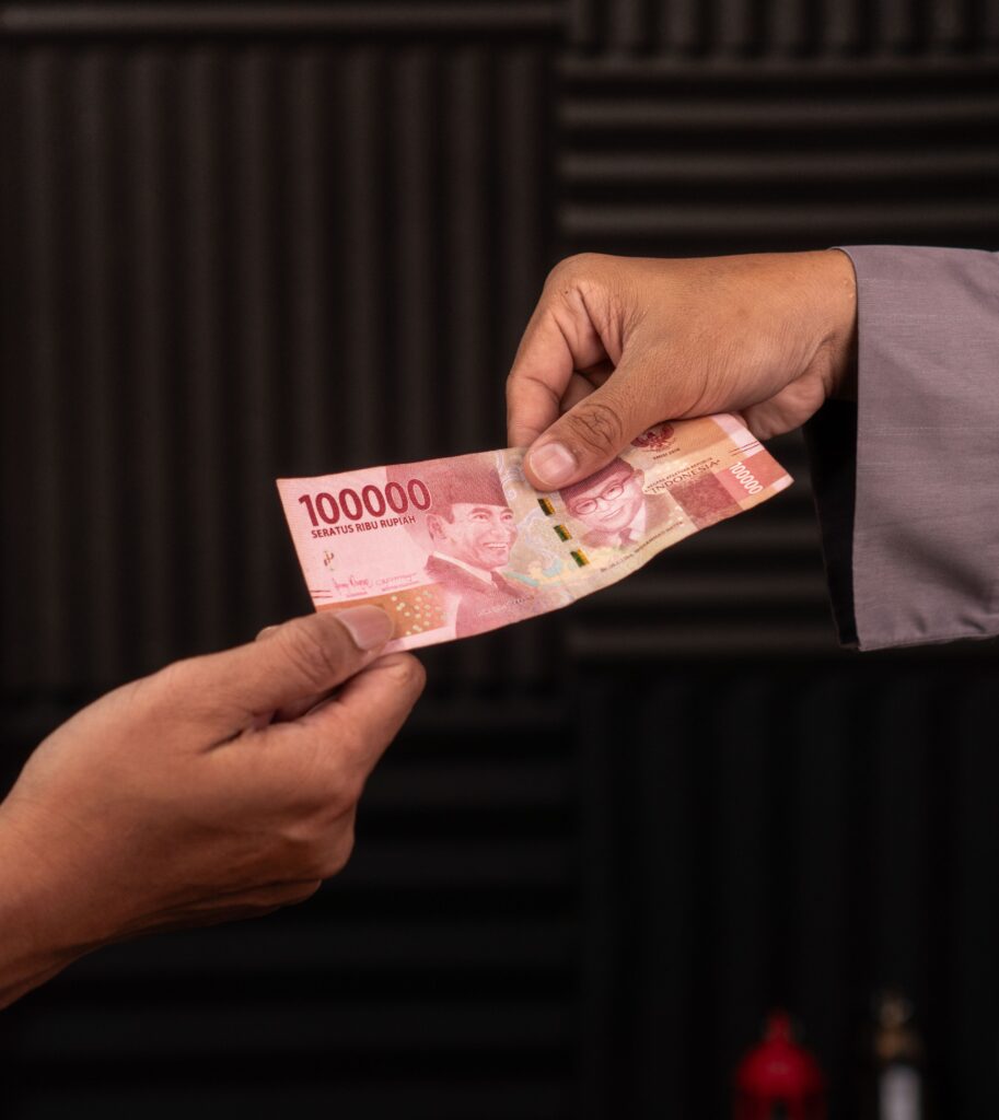 Hand exchanging Indonesian rupiah banknote as Bank Indonesia expands monetary incentives