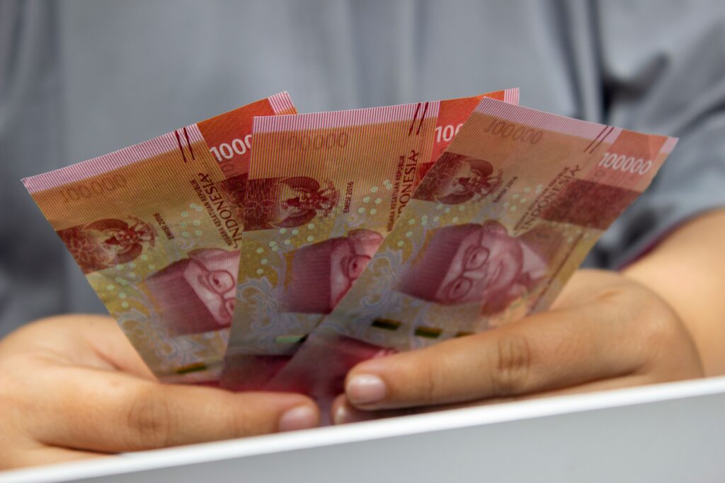 A person holding Indonesian rupiah banknotes, representing currency stability, exchange rates, and Indonesia's financial market.