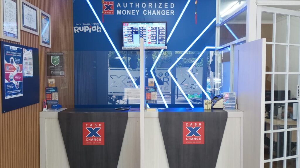 Money Changer Exchange Rates displayed at an authorized Cash X Change counter with a visible foreign currency rate board